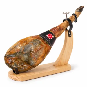 Cortijo de Canata Serrano ham aged 15 months, whole and bone-in, with its black brand label, on a wooden ham stand