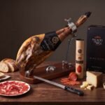 Cinco Jotas Grand Ham Box with Stand & Knife Cinco Jotas Ibérico de Bellota ham on a folding ham stand with 5J lomo, olive oil gift case, Manchego and anchovy-stuffed olives